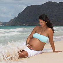 Sitting on the sand with crashing waves at Bellows Beach Maternity Photography Session