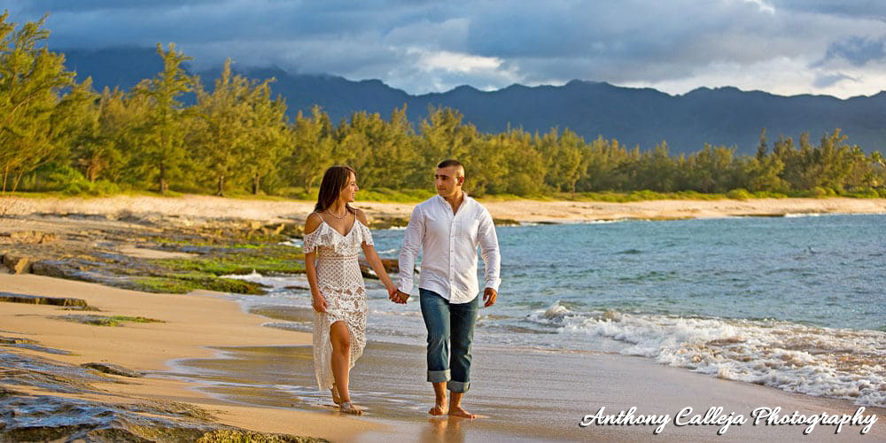 An Engagement Couple holding hands walking on the sands of Papailoa Beach, North Shore, Oahu