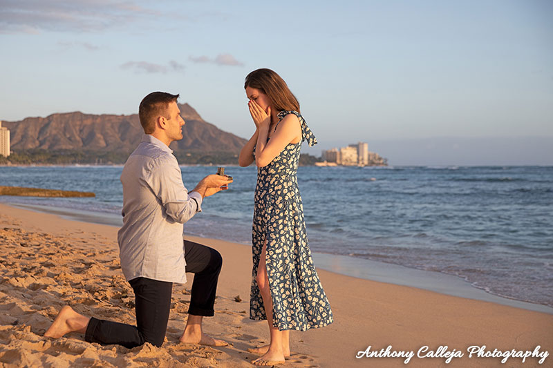 Jesse on bended knee, proposing to Ariella at Waikiki Beach