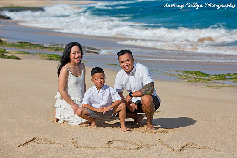 photo of a family of three sitting on the sand at Papailoa Beach, North Shore, Oahu
