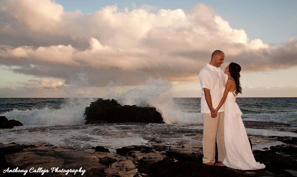 Waikiki Wedding Photography - Wedding Couple holding hands, crashing waves, puffy white clouds, Sandy Beach Oahu Hawaii